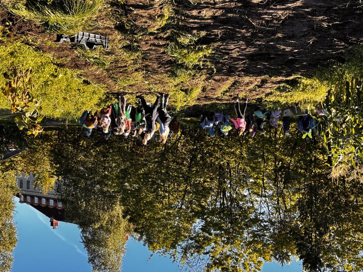 en gruppe mennesker som står på en høyde med trær og en bygning i bakgrunnen