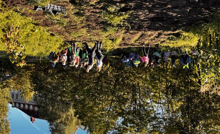 en gruppe mennesker som står på en høyde med trær og en bygning i bakgrunnen