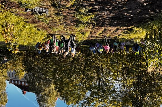 en gruppe mennesker som står på en høyde med trær og en bygning i bakgrunnen
